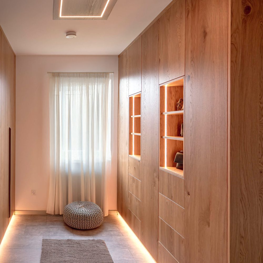 Maßgefertigter Flurschrank aus Holz mit beleuchteten Vitrinenfächern und integriertem Stauraum