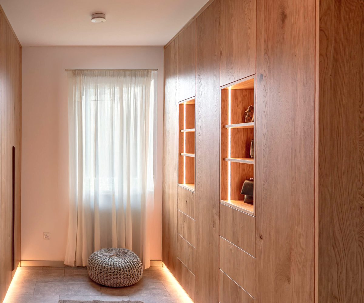 Maßgefertigter Flurschrank aus Holz mit beleuchteten Vitrinenfächern und integriertem Stauraum
