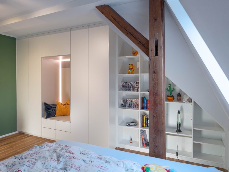 Dachschrägenschrank matt weiss Inlay hellgrau hinter Holzpfosten