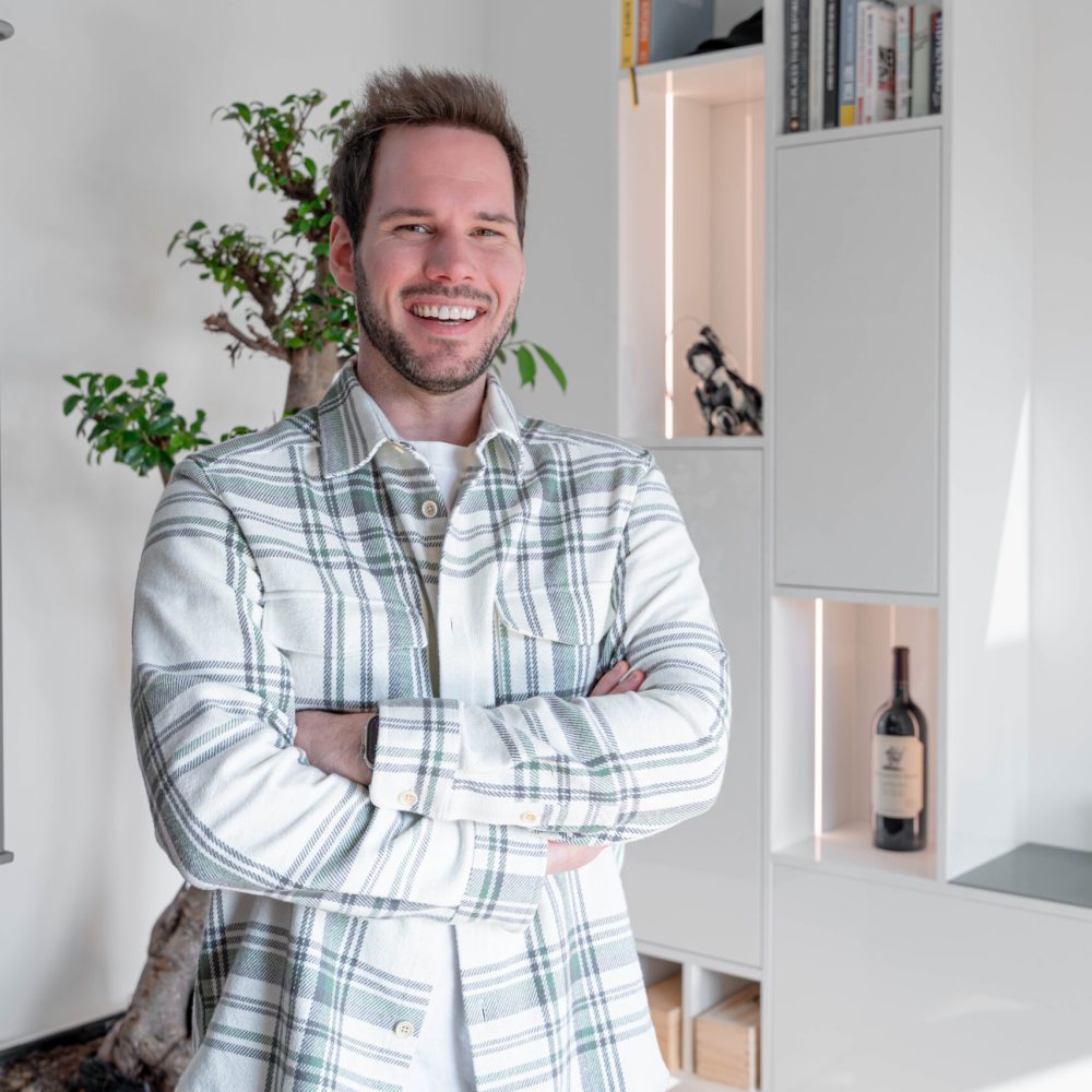 Kunde steht vor maßgefertigter Wohnwand mit integrierter Beleuchtung im Wohnbereich