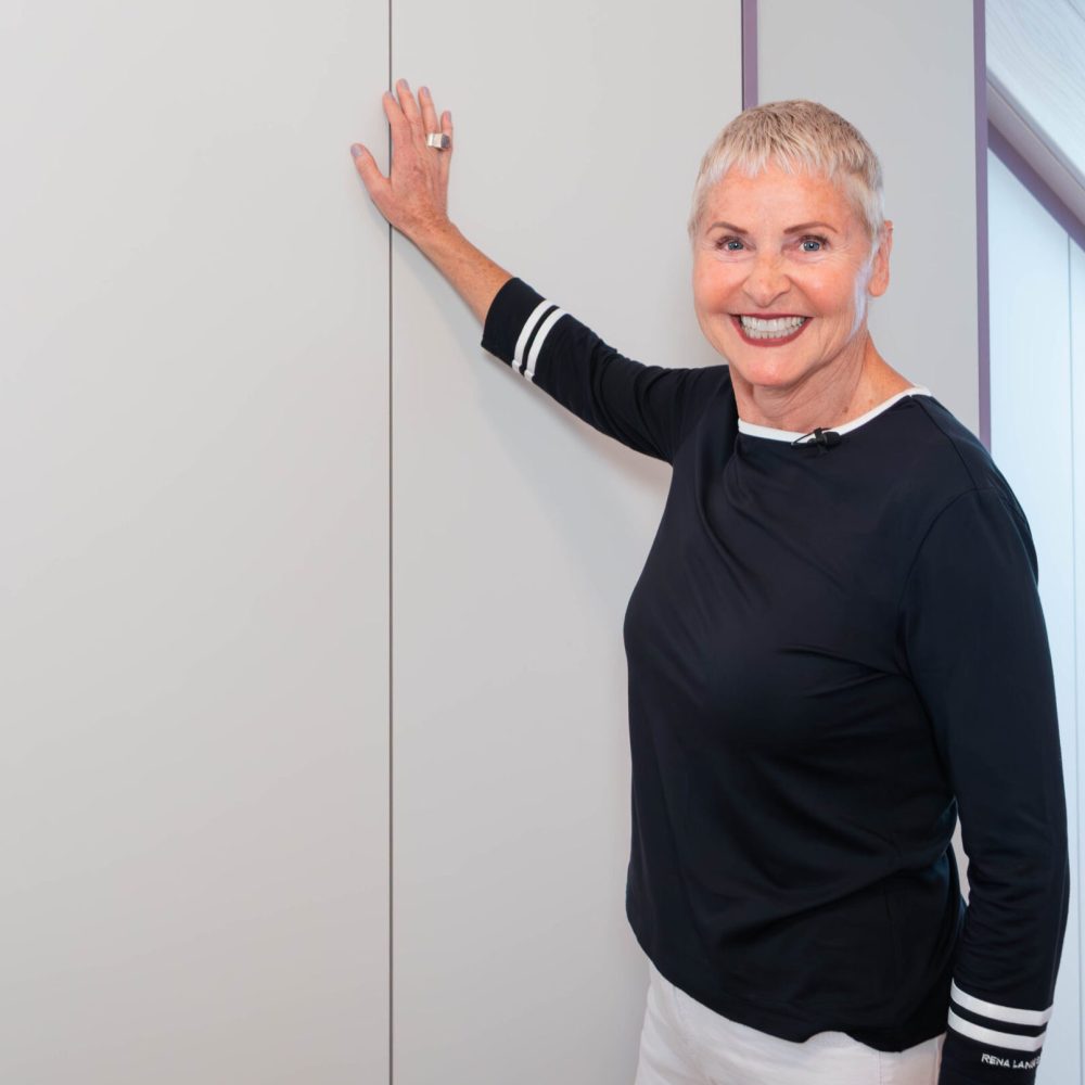 Kunden Testimonial steht vor maßgefertigtem weißen Dachschrägenschrank