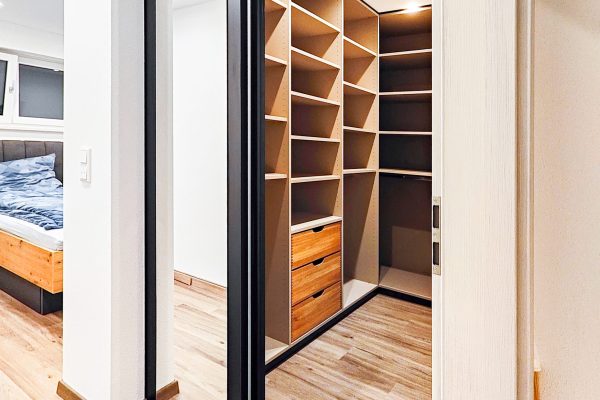 Begehbarer Kleiderschrank mit geöffneten Schiebetüren