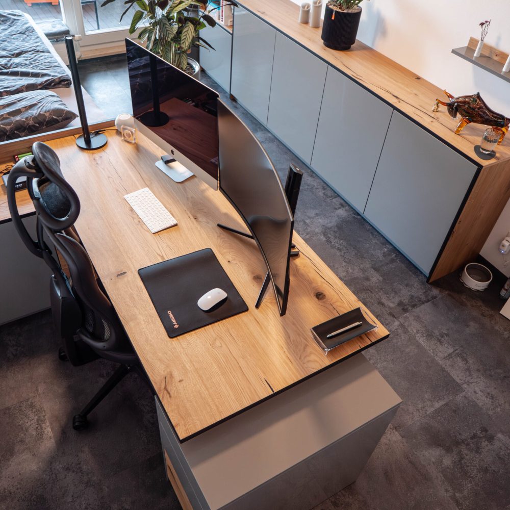 Maßgefertigte Büroraumausstattung mit integriertem Arbeitsplatz, durchgehender Schranklösung, grauen Fronten und Eichenholz-Oberflächen im modernen Homeoffice