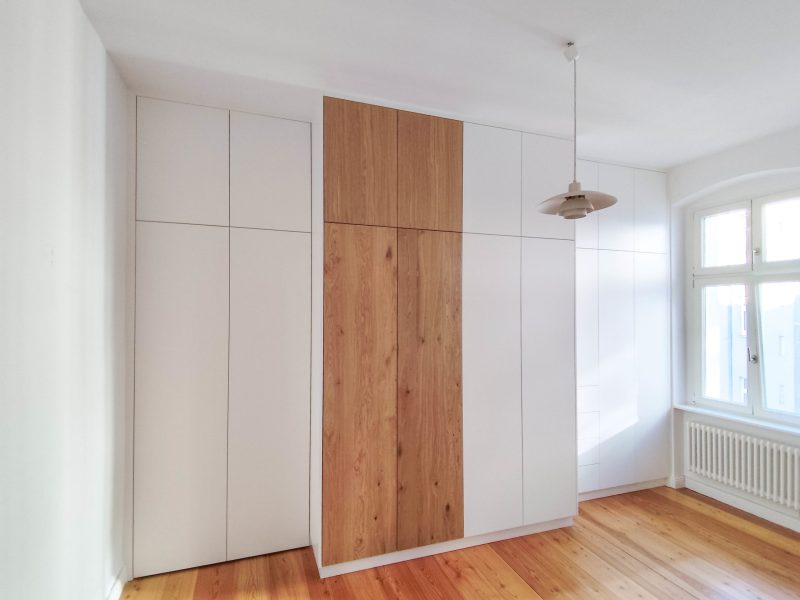 Maßgefertigter Einbauschrank in Weiß mit mittiger Holzfront im Schlafzimmer