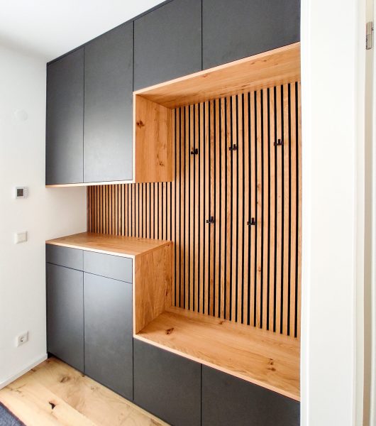 Graue Garderobe mit Holzpaneelen und Sitzfläche