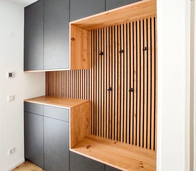 Graue Garderobe mit Holzpaneelen und Sitzfläche