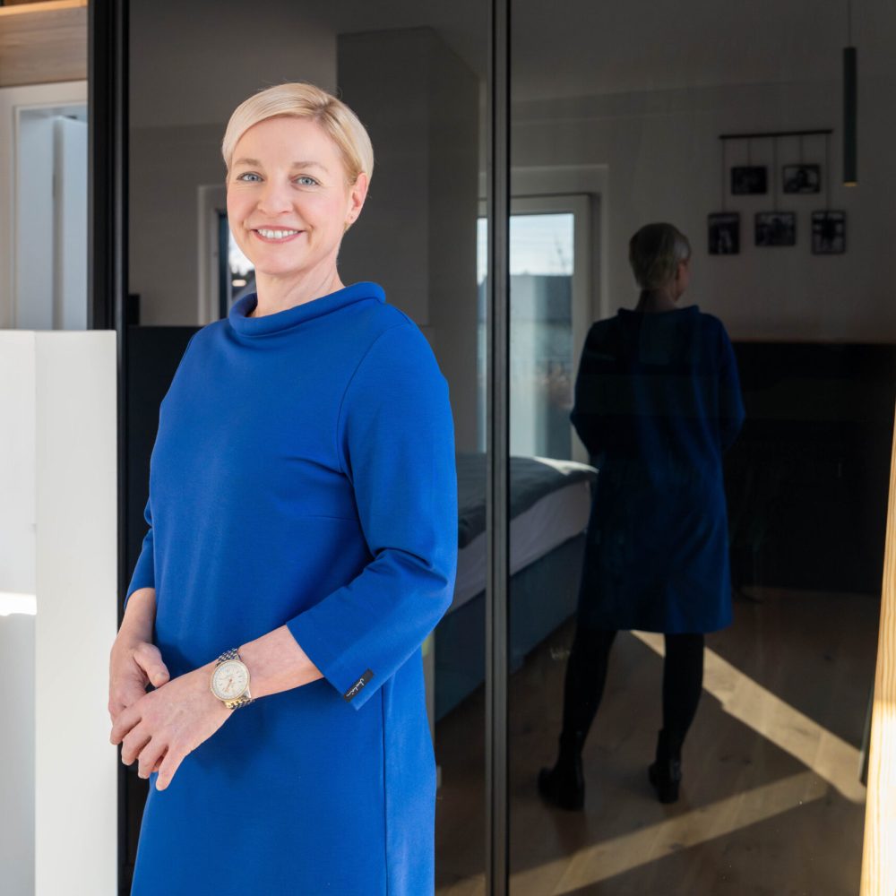 Kunden Testimonial steht vor maßgefertigtem Schlafzimmerschrank mit Spiegelfront